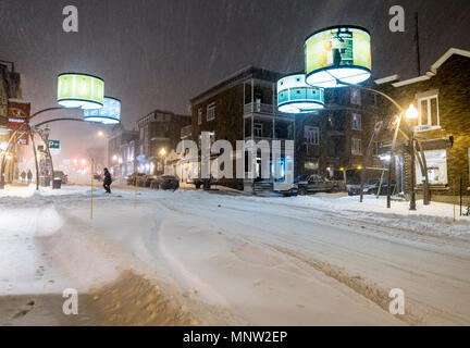 Rue Cartier in Quebec during a blizzard: The fanciful street lights that decorate this usually busy commercial street light the driving snow during a blizzard . Pedestrians work their way thorugh the snowy streets. Stock Photo