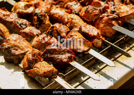 Meat on grill or shish kebab process of cooking. Fried on the on skewers on hot charcoal. Traditional eating for picnic. Close-up. Stock Photo
