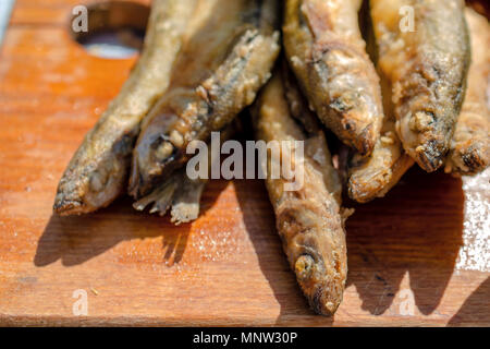 Fresh fried small fish. Delicious seafood on a wooden background. Selective focus. Close-up. Stock Photo