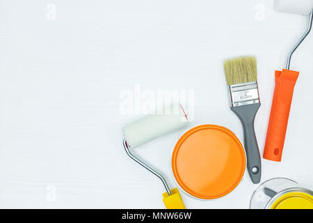 painting tools on wooden desk. tins with paints, paint brushes and rollers. flat view Stock Photo