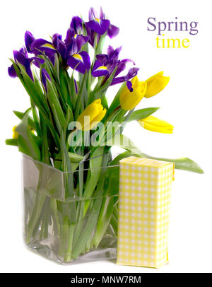 Yellow tulips and blue irises in a vase near a square gift box Stock Photo