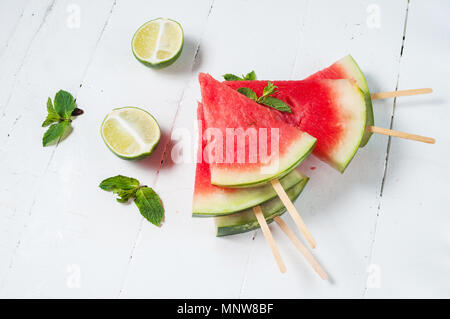 Watermelon slice popsicles and lime on rustic wood background. Stock Photo