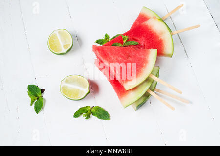 Watermelon slice popsicles and lime on rustic wood background. Stock Photo