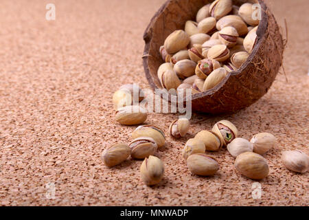 handmade bowl of coconut with pistachios on a wooden table. Close-up. Stock Photo