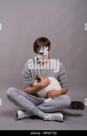 Young handsome man wearing white mask against gray background Stock Photo