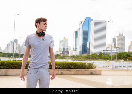 Young handsome man wearing headphones while relaxing at the park Stock Photo