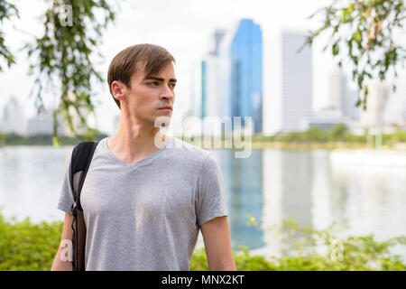 Young handsome man with backpack relaxing at the park Stock Photo