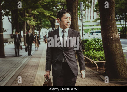 Japanese businessman walking outdoors - Asian man with elegant suit Stock Photo