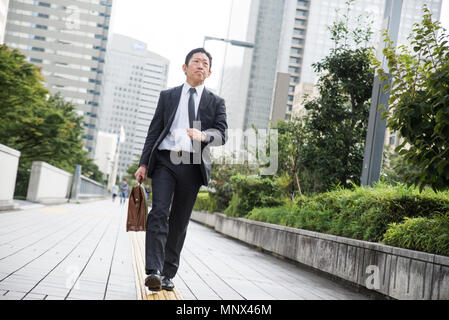 Japanese businessman walking outdoors - Asian man with elegant suit Stock Photo