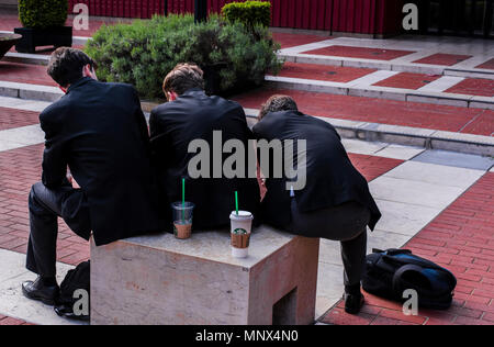 Three boys, sitting on seat, forming sloping shape, rear view, London, England, UK Stock Photo