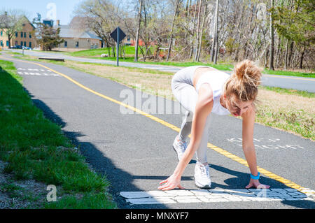 Sprinter woman getting ready to start on the running track. Female runner is waiting for the start signal Stock Photo