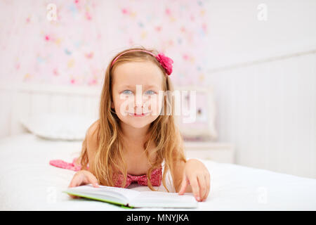 Adorable little girl in her room reading Stock Photo