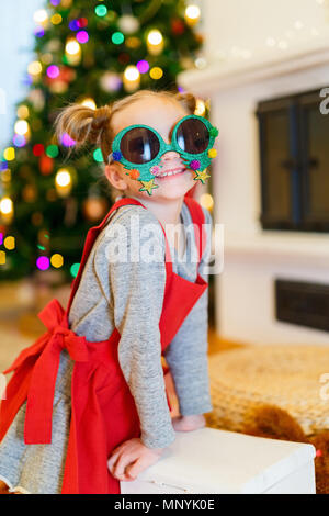 Adorable little girl wearing funny Christmas glasses in home beautifully decorated with Christmas tree and lights Stock Photo Alamy