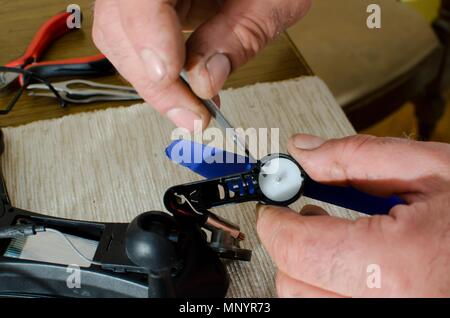 hands of man repairing small black drone with blue propeller Stock Photo