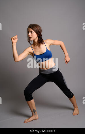 Young beautiful woman ready for gym against gray background Stock Photo