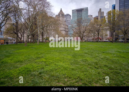 The green grass and tree in the Battery Park against the skyline of Manhattan in New York, USA. April 30, 2018. Stock Photo