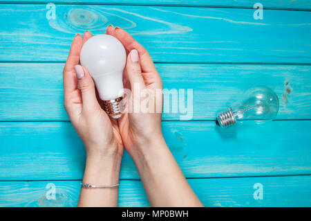 female hand selected led lamp of innovation electric lamp on blue wood background. Stock Photo