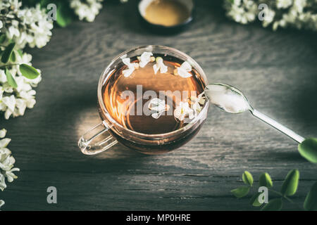 Cup of tea and acacia flowers on rustic wooden background, top view. Healthy seasonal herbal tea Stock Photo