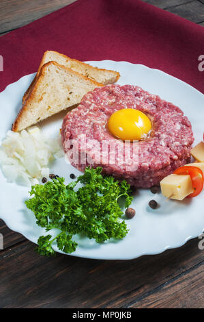 Beef tartare with bread and fresh onion on a wooden background Stock Photo