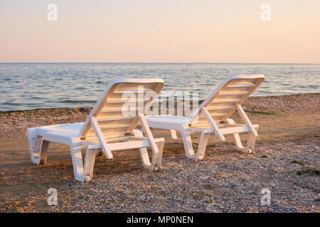 Close up two half-turn chaise longues on the sand. Stock Photo