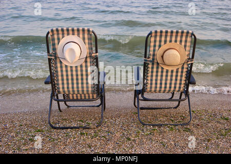 Close up backside view lounge chairs at a coastline. Stock Photo