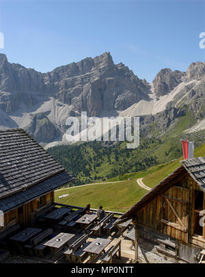 Hikers at the Medalges Alm view the Odle group of mountains, part of The Dolomites in Puez-Odle nature park, South Tyrol, Province of Bolzano, Italy. Stock Photo