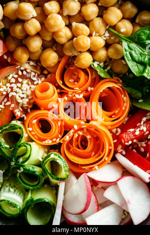 Colorful Buddha Bowl with chickpeas, carrots, tomatoes, cucumbers, radish and peppers on a wooden table. Vegetarian salad. Top view. Close up. Stock Photo