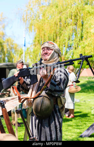 Popular Salute to the 40s event at Sandwich town, Kent. Young man Re-enactor dressed as Arab Bedouin holding machine gun for people to see. Stock Photo