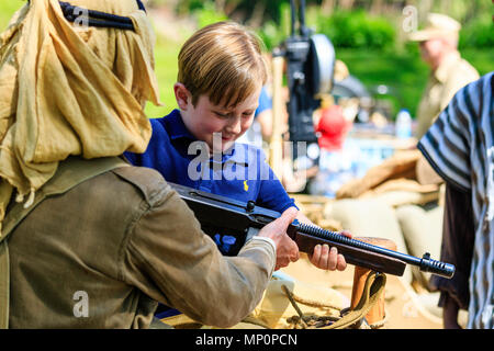 Salute to the 40s popular event at Sandwich in Kent. World war two soldier from the Desert Rats re-enactment group showing young boy child how to hold Stock Photo