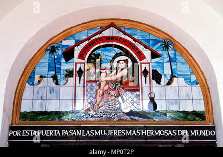 An historic stained-glass window and a greeting in Spanish -- 'Through this door pass the most beautiful women in the world' -- greets guests above the archway entrance to the landmark Rosarito Beach Hotel that opened in the 1920s a few miles south of the U.S.-Mexican border near Tijuana in Baja California, Mexico, North America. The female featured in the artwork is Mexican actress Maria Luisa Chabert, future wife of the man who later bought the 10-room hostelry and started its growth to the modern oceanfront resort that it is today. Stock Photo