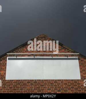 Blank Billboard Sign On An Old Red Brick Factory Building With Moody Sky Stock Photo