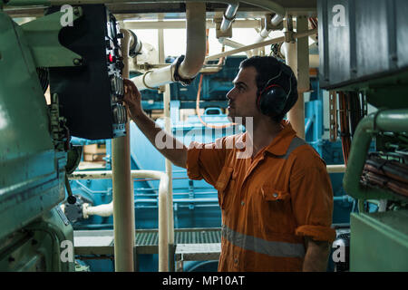 Marine engineer inspecting ship's engine in engine control room Stock Photo