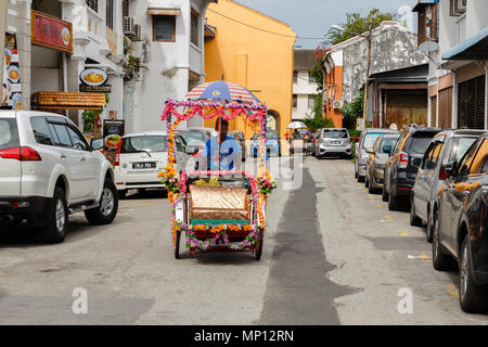 Rickshaw driver is driving down the street in Georgetown. Stock Photo