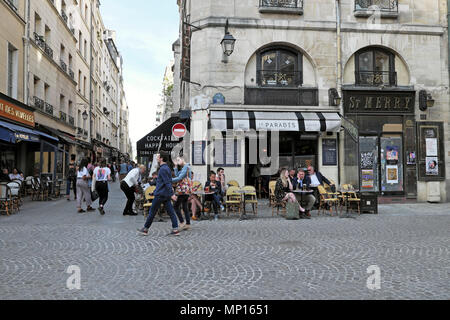 Couple walking by people sitting at tables outside Le Paradis on corner of  Rue de la Verrerie & Rue Saint-Martin Paris France Europe EU KATHY DEWITT Stock Photo