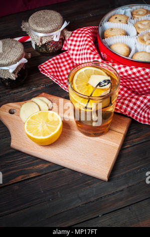 cup black tea with lemon, ginger and cookies on dark wood. Stock Photo