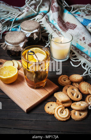 cup black tea with lemon, ginger and cookies on dark wood. Stock Photo