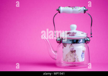 Heat resistant glass teapot with tea strainer on pink Stock Photo