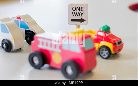 A One Way sign is shown next to a childs toy cars Stock Photo