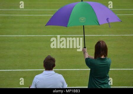 An umbrella held over a resting tennis player at Wimbledon Stock Photo