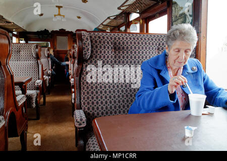 An older woman drinking tea on the Peak Rail steam train in Bakewell, Derbyshire Stock Photo