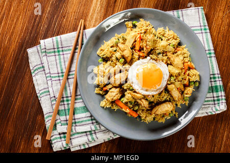 Fried rice nasi goreng with chicken egg and vegetables on a plate. Indonesian cuisine. Top view Stock Photo
