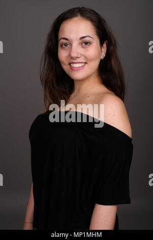 Young beautiful woman wearing black off-shoulder top against gra Stock Photo