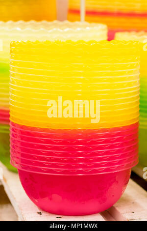 Plastic multi-colored bowls on the shelf in the store. Stock Photo