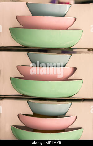 colorful deep plates in a cardboard box in the store. packed multicolored pans hang on the shelf in the store. Stock Photo