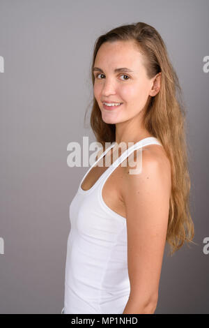 Young beautiful woman with long blond hair against gray backgrou Stock Photo