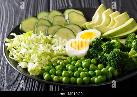 Healthy green food: fresh vegetables avocado, peas, cabbage, cucumber, broccoli and boiled eggs close-up on a plate. horizontal Stock Photo