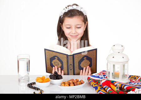 Young Muslim girl reading holy Quran ready for iftar( breakfast ) in Ramadan Stock Photo