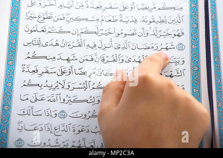 Muslim boy pointing to the word : Ramadan ( The holy Month ) while reading the Quraan in a mosque Stock Photo