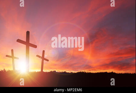 A silhouette of the crucifixion of Jesus Christ on a cross with 2 other robbers against a dramatic sunset. Sacrificial death of Jesus on Good Friday a Stock Photo