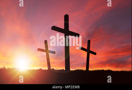A silhouette of the crucifixion of Jesus Christ on a cross with 2 other robbers against a dramatic sunset. Sacrificial death of Jesus on Good Friday a Stock Photo